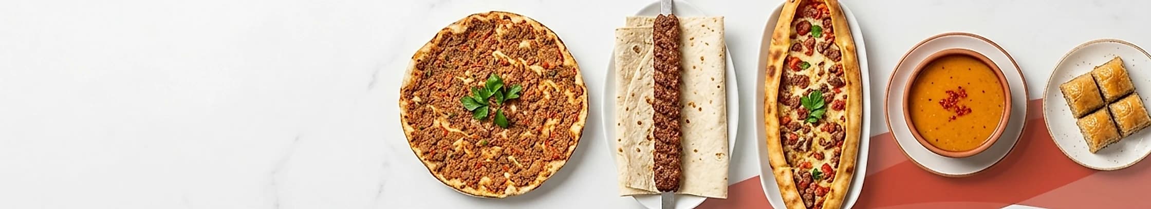 Beyaz mermer zemin üzerinde lahmacun, adana kebap, pide, mercimek çorbası ve baklava